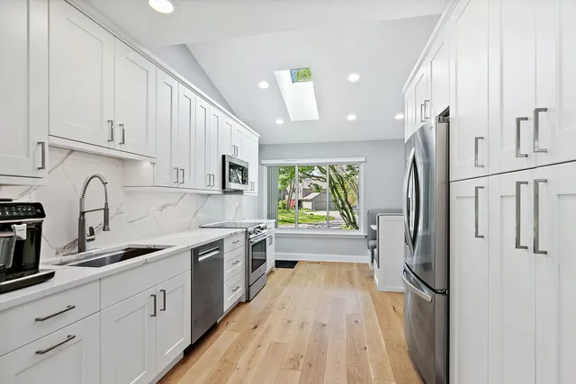 a kitchen with stainless steel appliances granite countertop a refrigerator sink and white cabinets