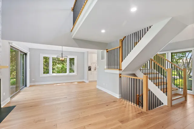 a view of an entryway with wooden floor leading to a furnished livingroom and windows