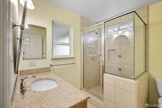 a bathroom with a granite countertop sink mirror and shower