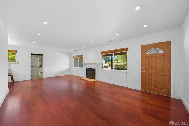 a view of empty room with wooden floor and window