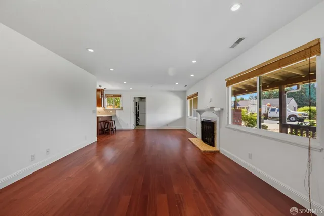 a view of a big room with wooden floor fire place and windows