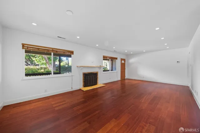 a view of empty room with wooden floor and fireplace