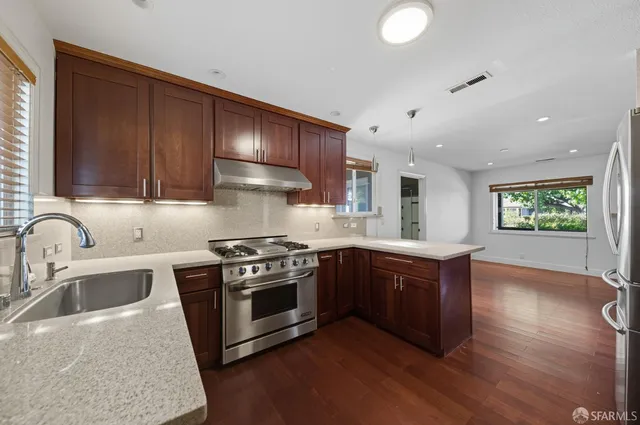 a kitchen with stainless steel appliances granite countertop a sink a stove and a wooden floors