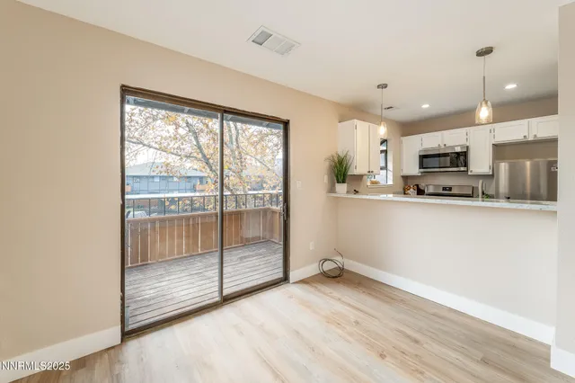 a view of a kitchen with wooden floor and stainless steel appliances