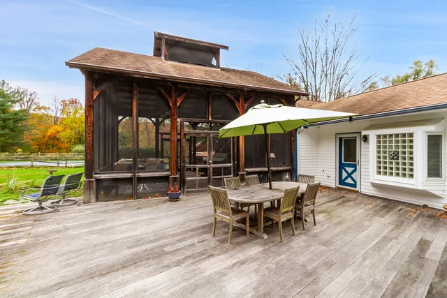 a view of a patio with table and chairs under an umbrella with wooden floor