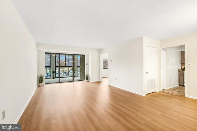 a view of an empty room with wooden floor and a window