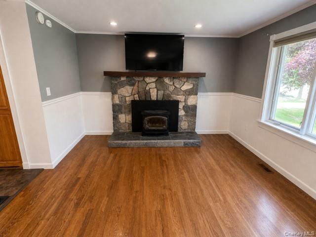 68 Whitford Road Westtown, NY 10998 - Photo 28 of 39 Living area featuring wood-finish flooring, a stone-clad fireplace with a wood-burning insert, a wood mantel, and wainscoting