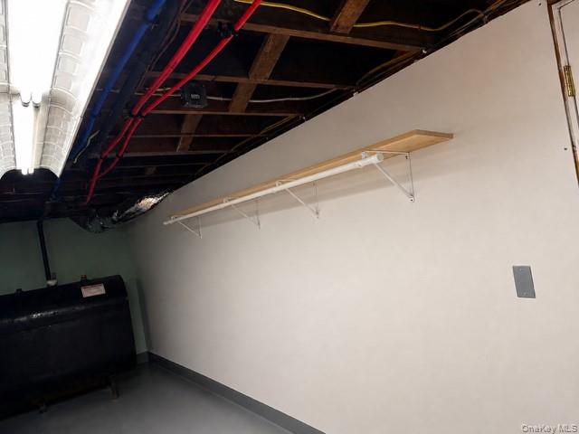 68 Whitford Road Westtown, NY 10998 - Photo 32 of 39 Unfinished utility area with an exposed ceiling, painted concrete flooring, and a wall-mounted wood-finish shelf with a hanging rod