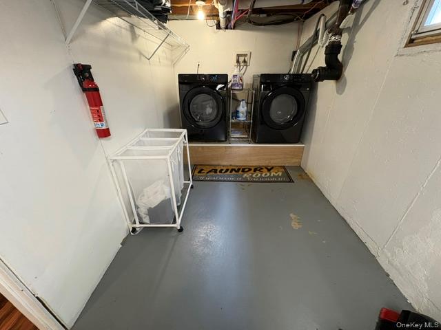 68 Whitford Road Westtown, NY 10998 - Photo 36 of 39 Dedicated laundry area featuring a raised platform, two front-loading machines, painted concrete flooring, and an overhead wire shelving unit
