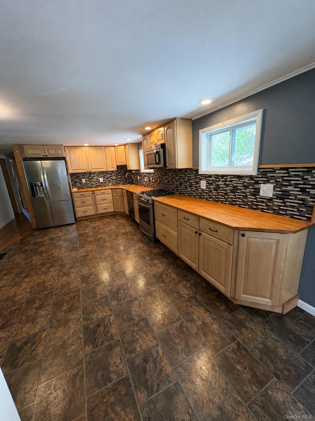68 Whitford Road Westtown, NY 10998 - Photo 39 of 39 Spacious kitchen featuring light wood cabinetry, wood-finish countertops, stainless steel appliances, and a mosaic tile backsplash