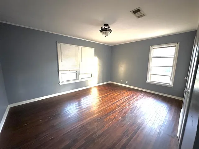 a view of empty room with wooden floor and fan