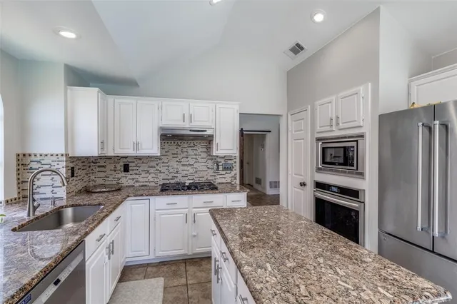 a kitchen with granite countertop a refrigerator stove and sink