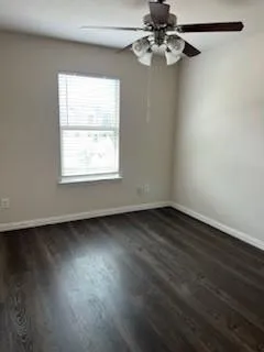 an empty room with wooden floor fan and windows