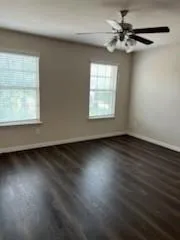 an empty room with wooden floor fan and windows