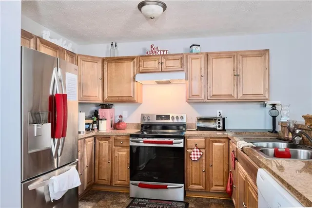 a kitchen with stainless steel appliances granite countertop a stove a sink dishwasher and cabinets with wooden floor