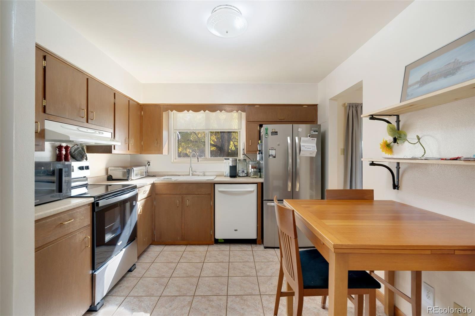 11760 West 32nd Avenue Wheat Ridge, CO 80215 - Photo 16 of 28 a kitchen with a stove a sink dishwasher a refrigerator with a dining table and chairs