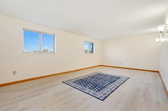 a view of an empty room with window and wooden floor