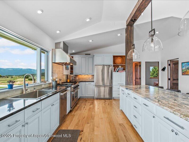 4100 County Road 103 Carbondale, CO 81623 - Photo 17 of 43 a large kitchen with stainless steel appliances a large counter top a stove a chimney a sink and a large window