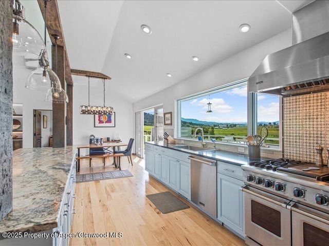 a kitchen with stainless steel appliances granite countertop a stove and a wooden floors