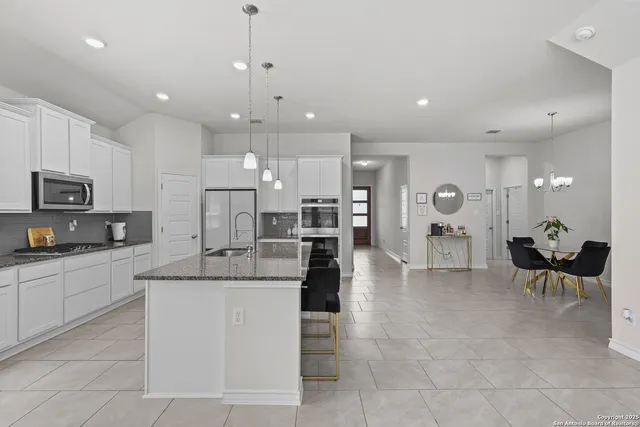a large white kitchen with kitchen island a stove a sink a table and chairs
