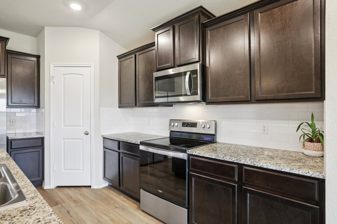 117 Break Avenue Taylor, TX 76574 - Photo 11 of 40 a kitchen with granite countertop cabinets stainless steel appliances and wooden floor