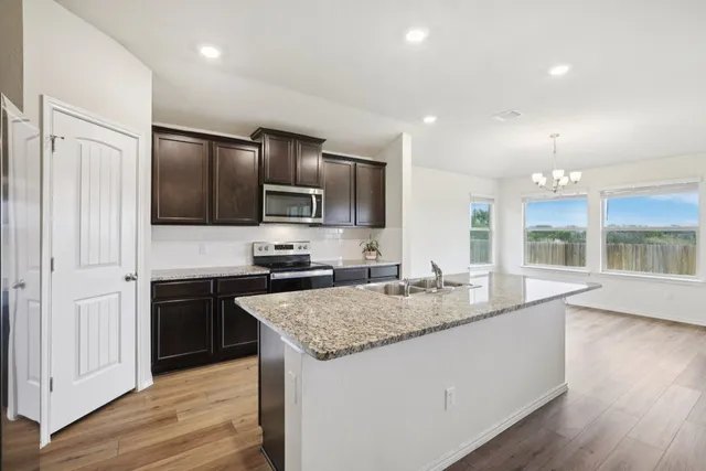 a kitchen with kitchen island granite countertop stainless steel appliances stove a sink and a refrigerator