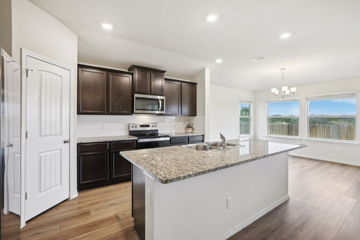 117 Break Avenue Taylor, TX 76574 - Photo 13 of 40 a kitchen with kitchen island granite countertop stainless steel appliances stove a sink and a refrigerator
