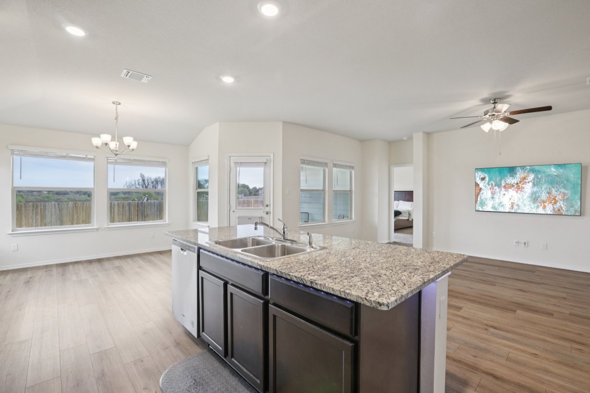 117 Break Avenue Taylor, TX 76574 - Photo 15 of 40 an open kitchen with granite countertop a stove and a wooden floor