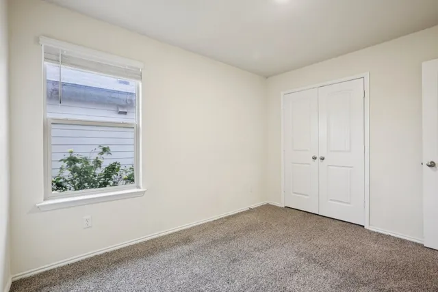 a view of an empty room with window and closet area
