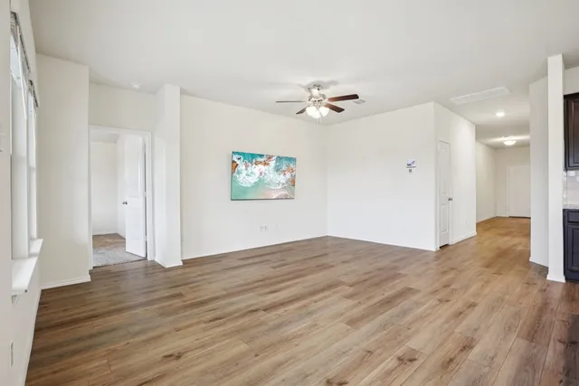 a view of empty room with wooden floor and ceiling fan