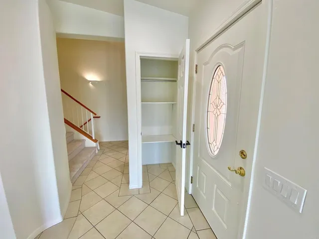 a view of an empty room with windows and chandelier fan