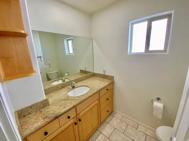a view of an empty room with window and chandelier fan
