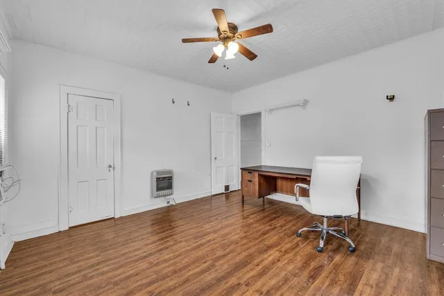 a workspace room with furniture wooden floor and a ceiling fan