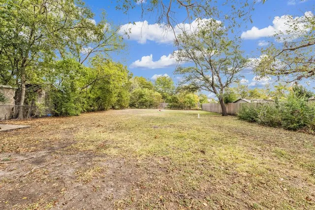 a view of yard with large tree and wooden fence