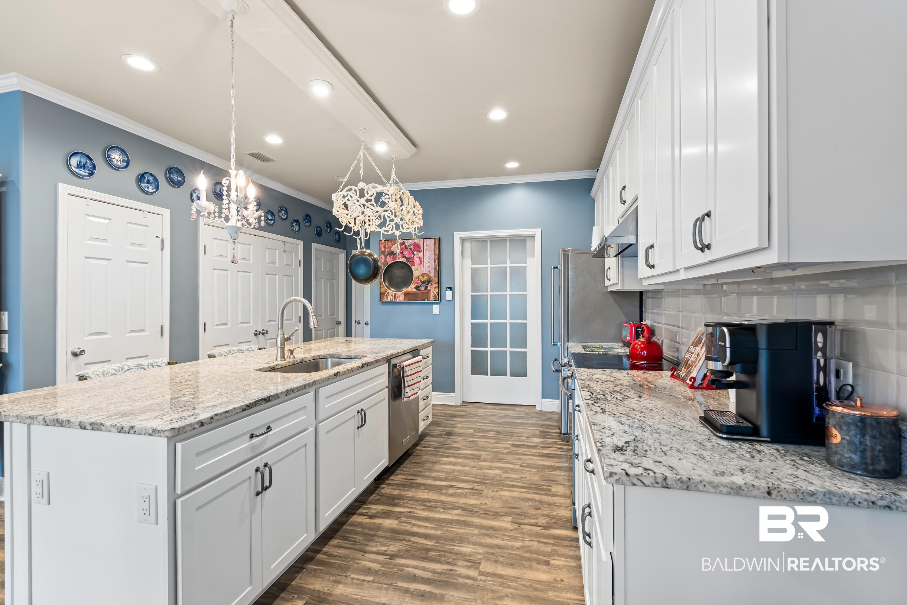 1113 Yellow Daisy Lane Foley, AL 36535 - Photo 12 of 35 Kitchen with ornamental molding, a kitchen island with sink, white cabinets, backsplash, and dark wood finished floors