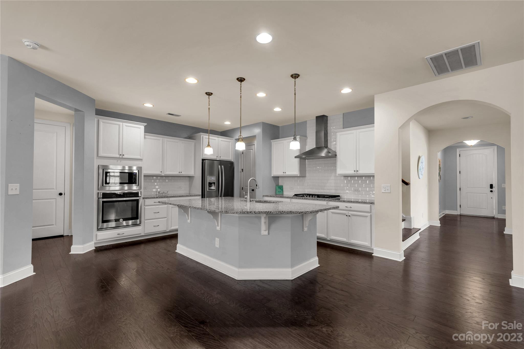 879 Pecan Tree Lane Fort Mill, SC 29715 - Photo 7 of 41 a kitchen with stainless steel appliances kitchen island granite countertop a stove a sink a refrigerator and white cabinets with wooden floor