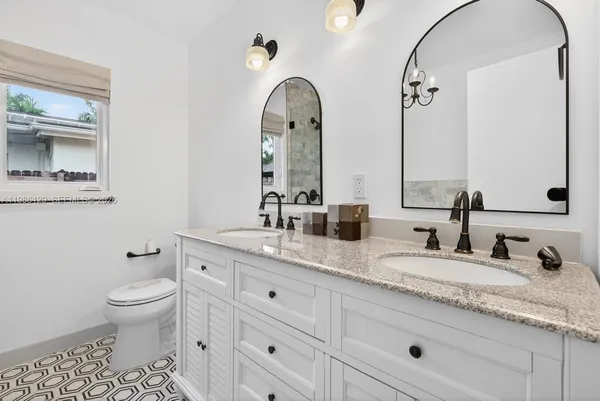 a spacious bathroom with a granite countertop toilet a sink and a mirror