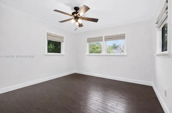 a view of an empty room with wooden floor and a ceiling fan