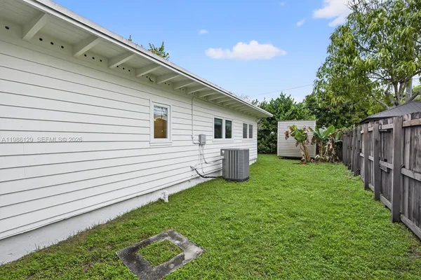 a view of backyard with barbeque grill and wooden fence