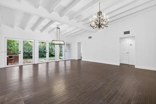 a view of an empty room with wooden floor and a chandelier
