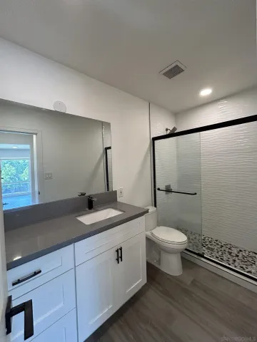 a bathroom with a granite countertop sink toilet and shower