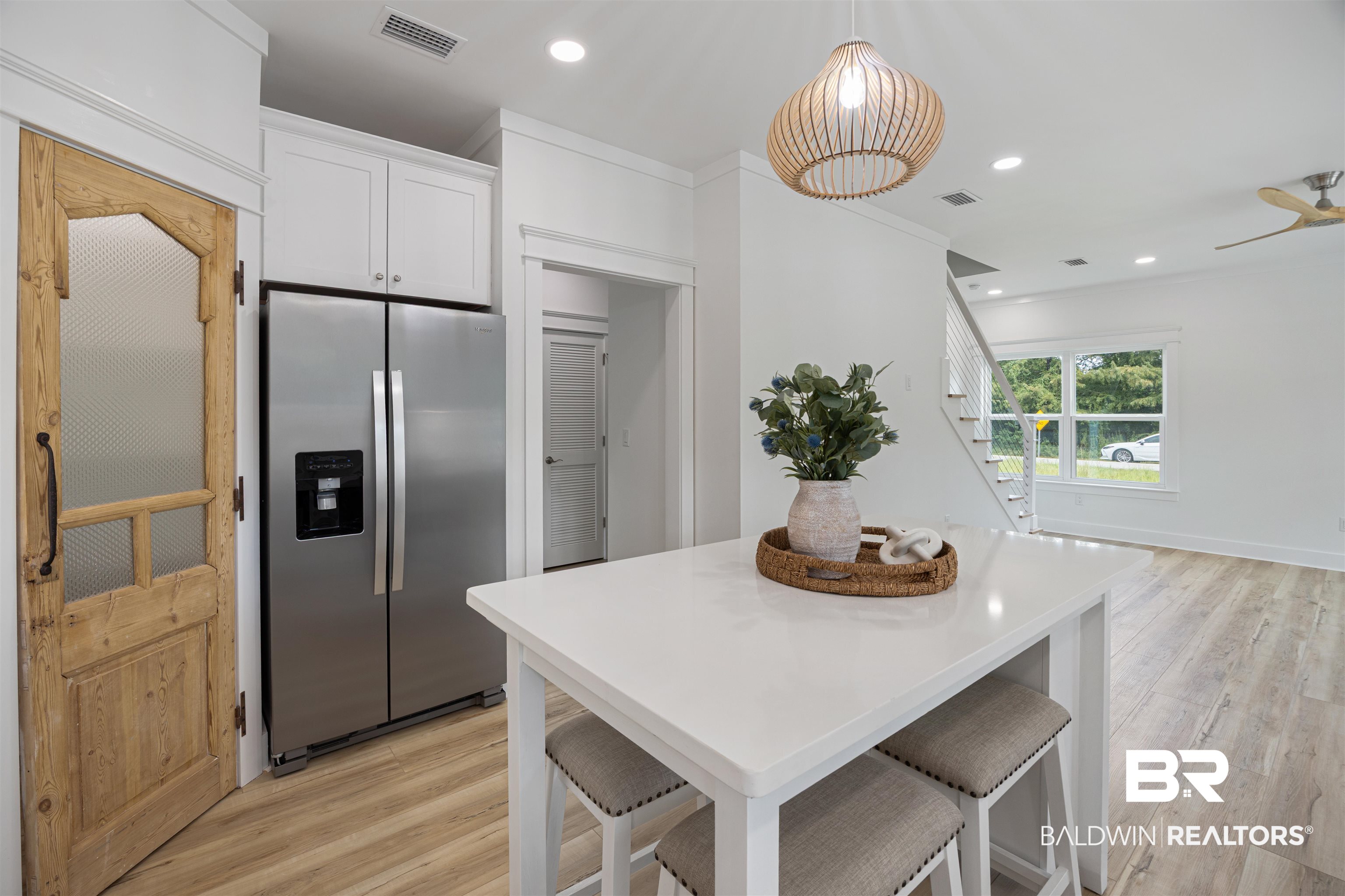 27591 Canal Road Orange Beach, AL 36561 - Photo 12 of 51 Kitchen featuring stainless steel fridge with ice dispenser, a kitchen bar, white cabinets, recessed lighting, and light wood-style floors