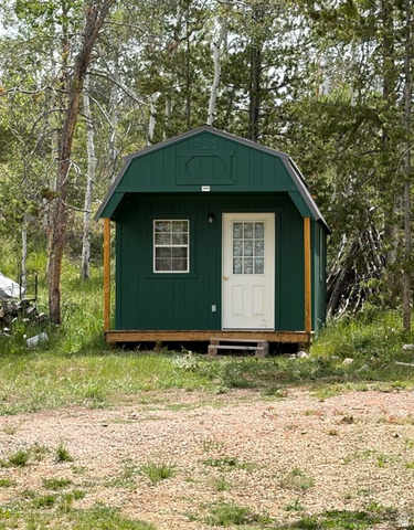 5782 Pineview Loop, Unit 921 Kamas, UT 84036 - Photo 22 of 29 Green gambrel-roofed structure with a white entry door and a single grid-paned window