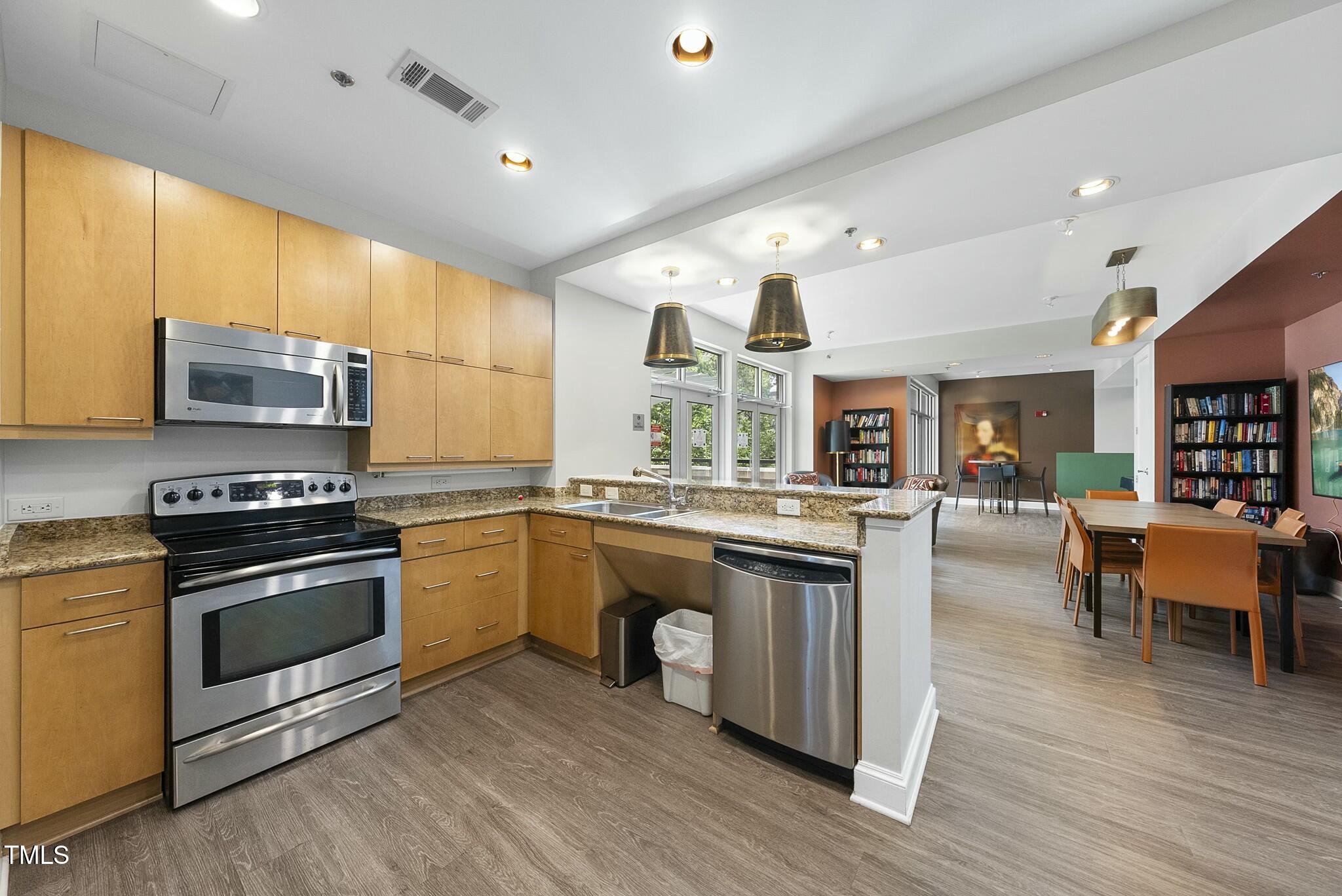 618 North Boylan Avenue, Unit 400 Raleigh, NC 27603 - Photo 18 of 28 a kitchen with stainless steel appliances granite countertop wooden cabinets a sink a stove a dining table and chairs