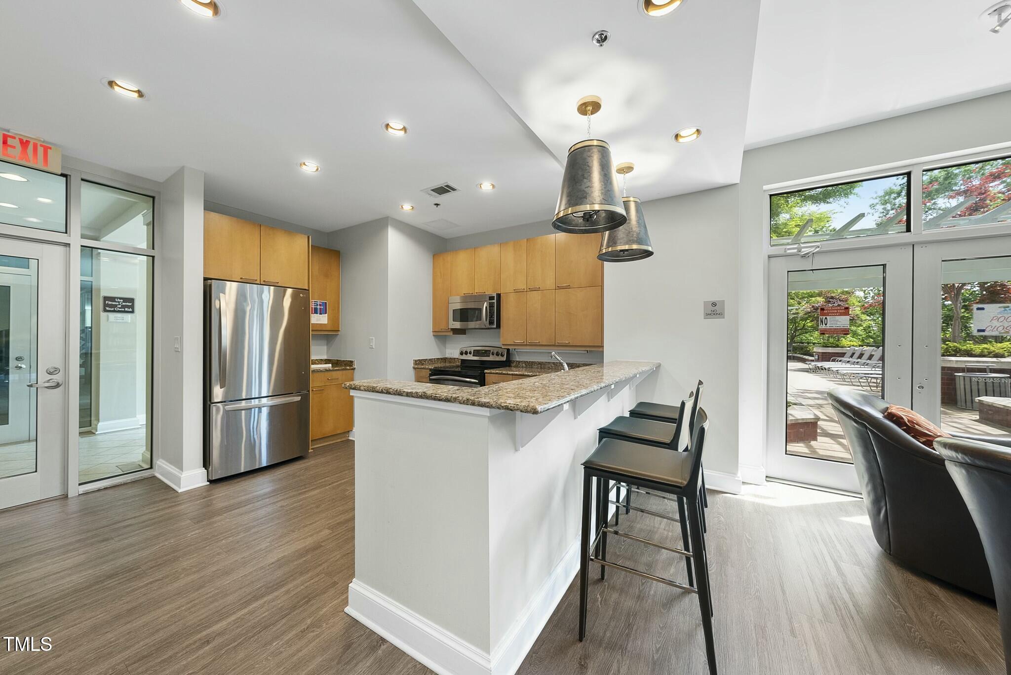 618 North Boylan Avenue, Unit 400 Raleigh, NC 27603 - Photo 19 of 28 a kitchen with stainless steel appliances kitchen island granite countertop a refrigerator a stove a sink dishwasher and a dining table with wooden floor
