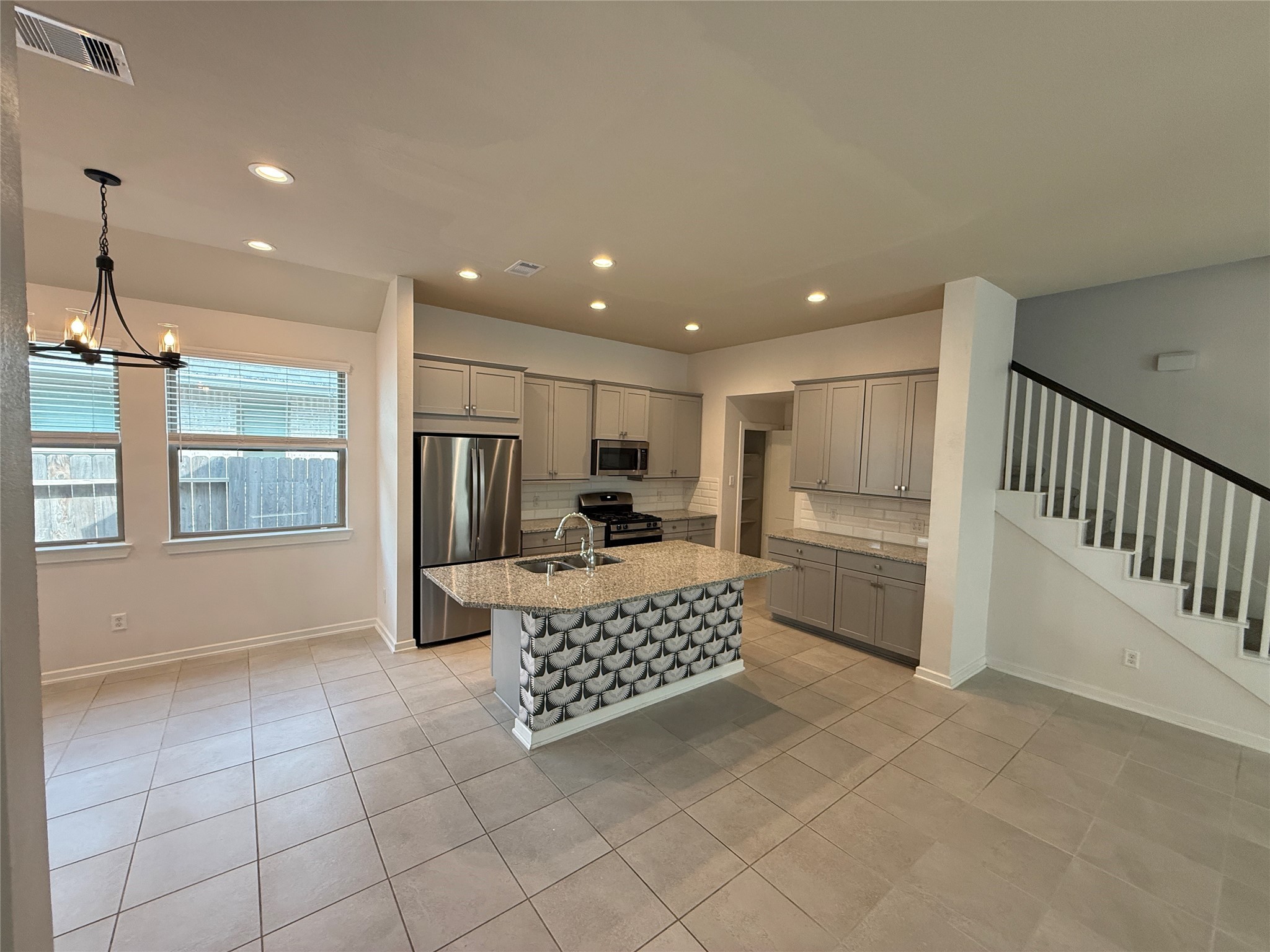 10534 Wild Chives Conroe, TX 77385 - Photo 9 of 24 a kitchen with stainless steel appliances kitchen island granite countertop a refrigerator and a stove top oven with white cabinets