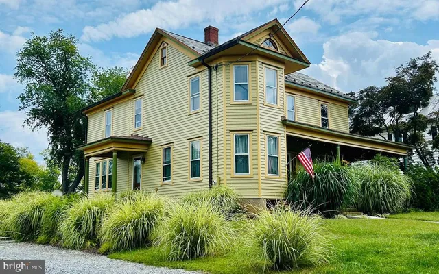 a view of a white house with large windows and a small yard