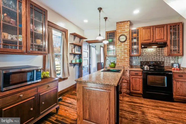 a kitchen with stainless steel appliances granite countertop a refrigerator a oven and a stove with wooden floor