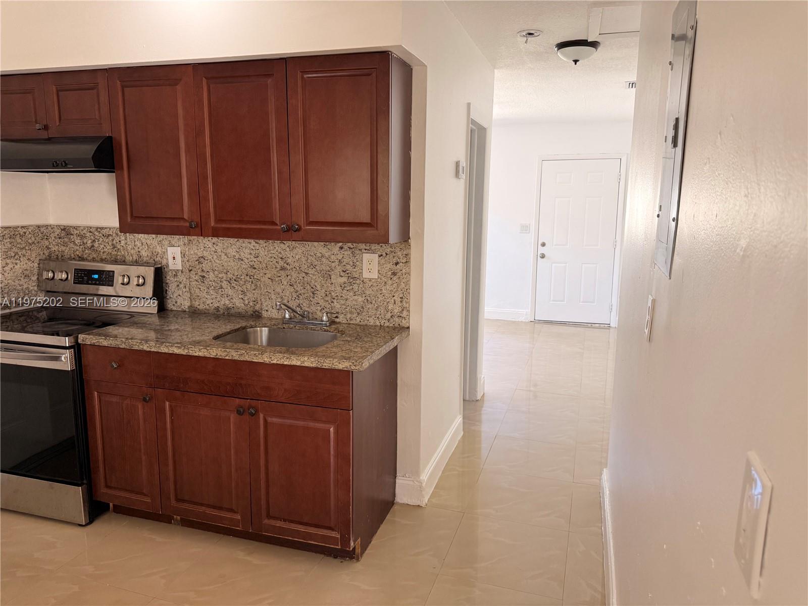 313 Northeast 57th Street, Unit 313 Miami, FL 33137 - Photo 9 of 13 a kitchen with stainless steel appliances granite countertop a refrigerator and a stove top oven