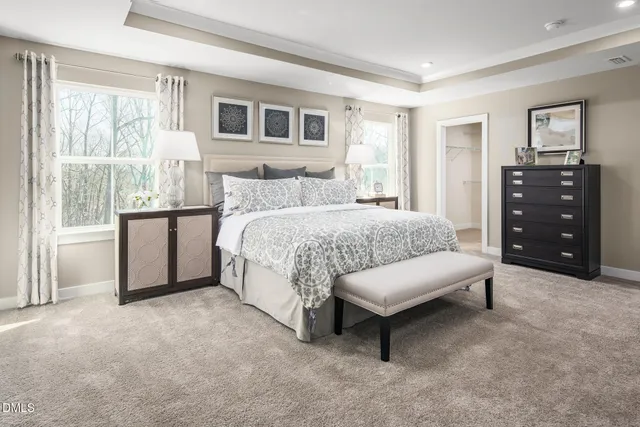 a spacious bedroom with a bed a dresser and a large window